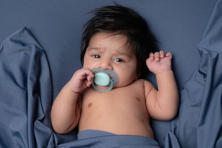 Close up photo of little adorable baby boy having black hair with pacifierの写真素材