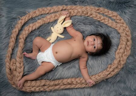newborn baby and his first toy Teddy Bear lying on the fur bedの写真素材