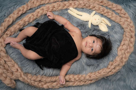 baby boy on grey background teddy bear covering by black shawlの写真素材