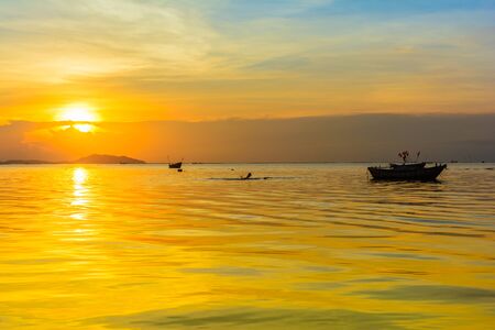 Beach and boat with warm light sunset backgroundの写真素材