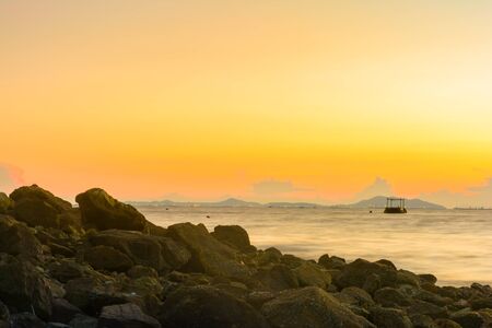 Rock on the beach and warm sky background with long exposureの写真素材