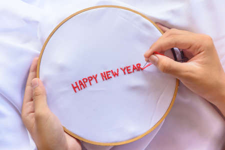 Handmade a text happy new year with sewing needle on white garment background. Concept and idea happy new year backgroundの写真素材