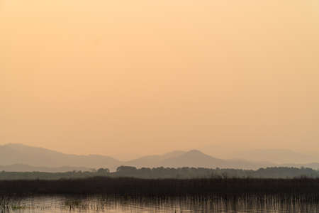Sunrise at water reservoir with mountain background. Nature park and outdoor landscape backgroundの写真素材