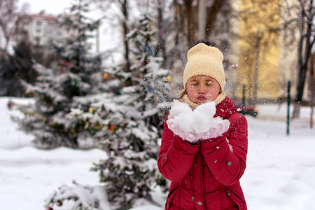 Girl blowing on the snow in his hands. Snow scatters.の写真素材
