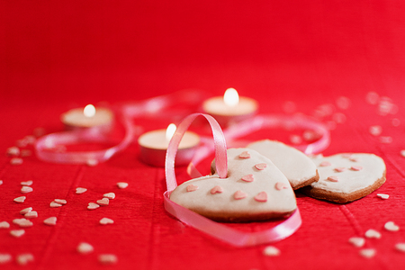 Ginger cookies with a pink ribbon on a red background and small figures scattered pink hearts.の写真素材