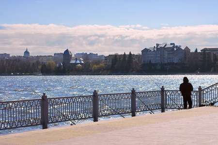 Fishing in the city. The man standing on the shore of the lake in backlit bait to spread out.の写真素材