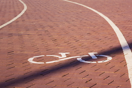 Bicycle route sign on the pavement in sunlight in a park. The ecological mode of transport. The path goes to the left.の写真素材