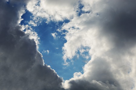 Background. White, gray and black clouds in the sky created an empty place in the blue sky.の写真素材