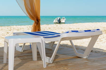 Wooden chaise longue, motorboat offshore in the seaの写真素材