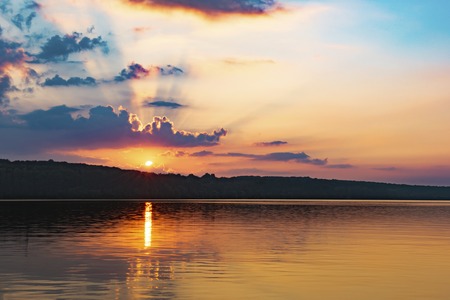Sunset over a lake, sky red and blue.の写真素材