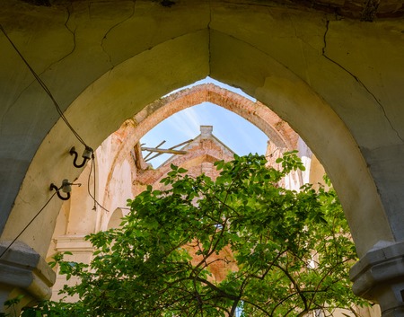 MYL'NE, TERNOPIL REGION, UKRAINE 12 MAY 2018: An old Catholic church that is not used and is abandoned to the backgrounds of a blue sunny sky with clouds. It was used as a storage facility for chemical fertilizers in the time of the USSR.のeditorial素材
