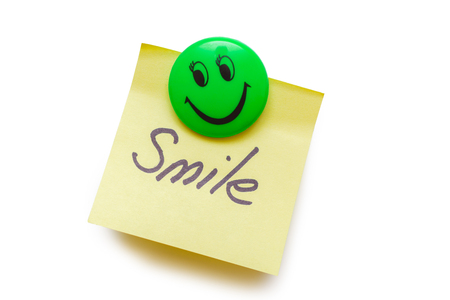 Yellow paper for notes with the words smile on a magnet isolated on whiteの写真素材