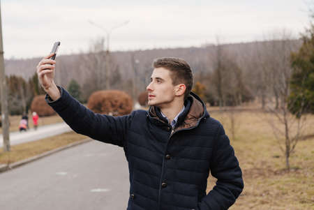 Beautiful business guy with phone in the autumn park