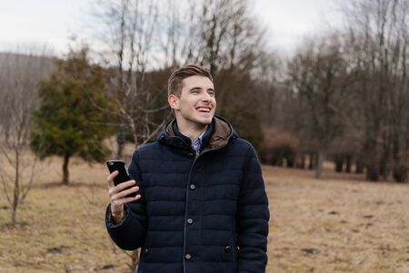 Beautiful business guy with phone in the autumn parkの写真素材