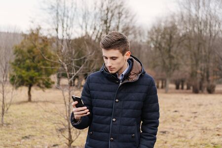 Beautiful business guy with phone in the autumn parkの写真素材