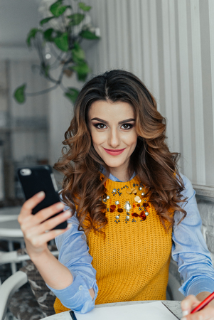Elegant lady working at a table in a cafe using phone. Sunshine. The positive modelの写真素材