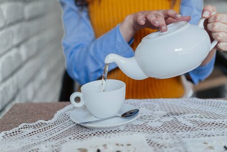 smiley woman pouring the cup of tea and smiling. shot in the cafeの写真素材
