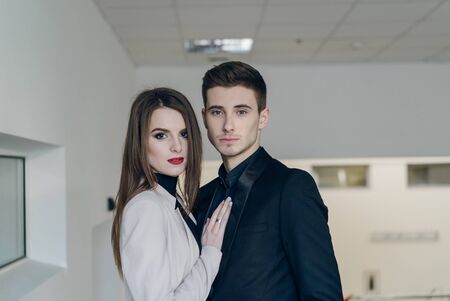 Portrait of young couple in love posing at studio dressed in classic clothesの写真素材
