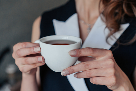Beautiful smiling young woman in glasses standing in coffee shop and using mobile phone while barista workingの写真素材