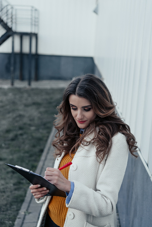 Serious business woman with tablet pc in front of office buildingの写真素材