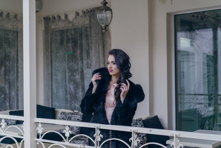 Beautiful girl model in a black coat posing for the cameraの写真素材