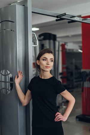 Beautiful girl in the gym posing for camera near simulators