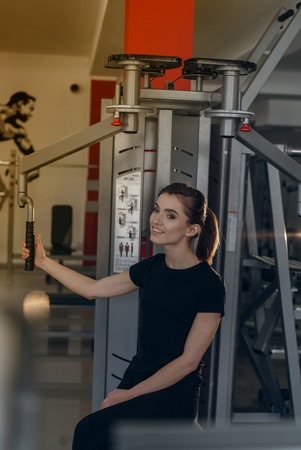 Beautiful girl in the gym posing for camera near simulatorsの写真素材