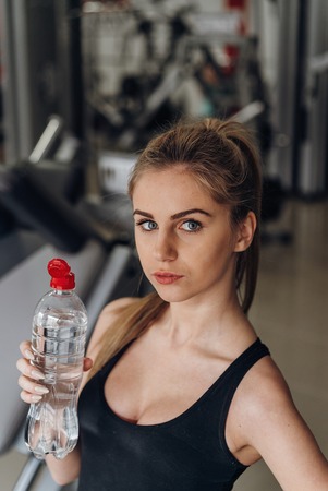 Portrait of happy woman wearing yellow tanktop looking aside with smile in gymの写真素材