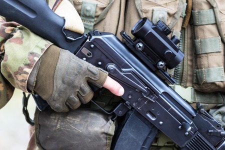 Soft focus. Soldier in camouflage holding a finger on the trigger of a Kalashnikov