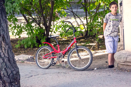 SAMARA REGION, RUSSIA - AUGUST 14, 2017: The sad Boy stands next to Bicycleのeditorial素材