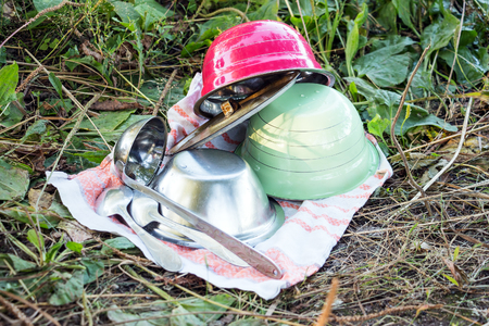 Kitchen utensils on a towel on the grass On the towel are plates, a ladle and spoonsの写真素材