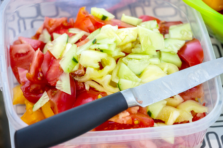 Tomato and Cucumber salad. Vegetarian Diet. On top of the salad lies a knifeの写真素材