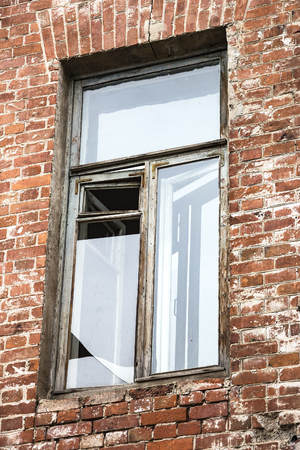 Broken window in an old house of red brickの写真素材