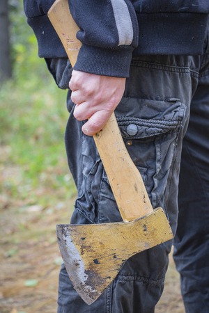 A man holds an ax in his hand while in the forestの写真素材