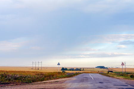 Landscape with a road running through the fields. In the background of dark cloudy skyの写真素材