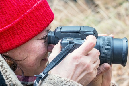 Soft focus. Female photographer looking through the viewfinder of the camera