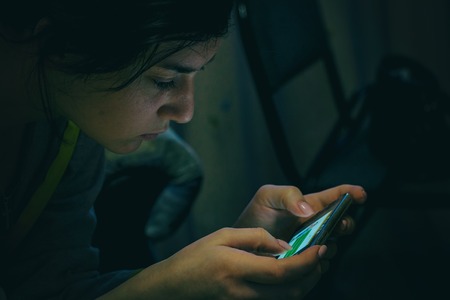 Girl in a dark room with a smartphone