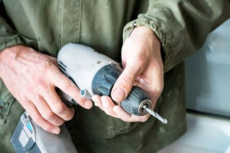 Carpenter keeps an electric drill in the handsの写真素材