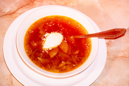 Soup with sour cream. There is a spoon in the plate