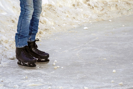 Men's legs in jeans with the put on skates stand on iceの写真素材