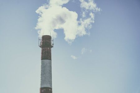 The smoke from a factory chimney on background of blue skyの写真素材