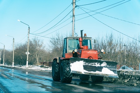 Tractor with snowplow on the street of the city