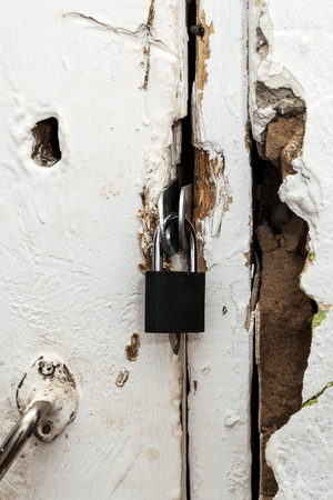 Small closed lock on an old white doorの写真素材