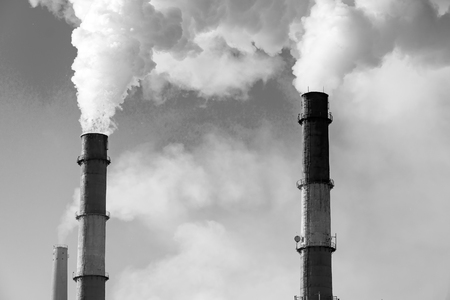 Factory chimneys smoke in the background of cloudy sky. Black and white photoの写真素材
