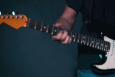 Blurred image. A gitar player with a guitar in a dark roomの写真素材
