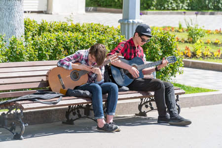 SAMARA, RUSSIA - JUNE 21, 2018: Two young street musicians with guitars on a Park bench