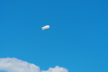 Large white air balloon in the shape of an airship in the blue sky