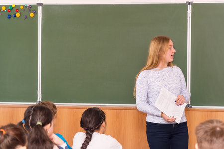 CHAPAEVSK, SAMARA REGION, RUSSIA - OCTOBER 24, 2018: Young teacher woman in front of the class at the blackboard