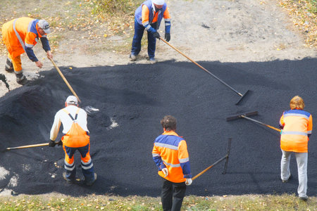 CHAPAEVSK, SAMARA REGION, RUSSIA - OCTOBER 17, 2018: Road street repairing works. Construction workers during asphalting road. Manual labor in constructionのeditorial素材