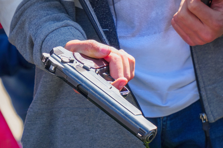 Gun in the hand of a man on a natural backgroundの写真素材